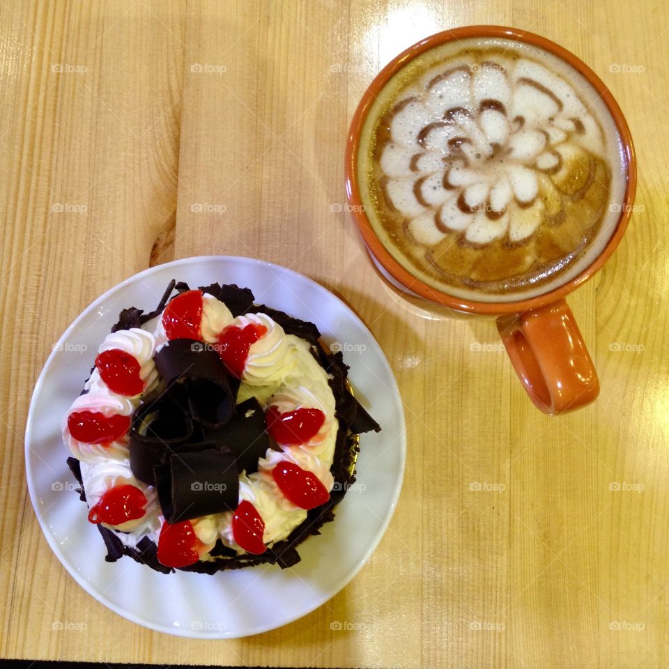 A cup of latte with black forest flavored cake for a rainy day.
