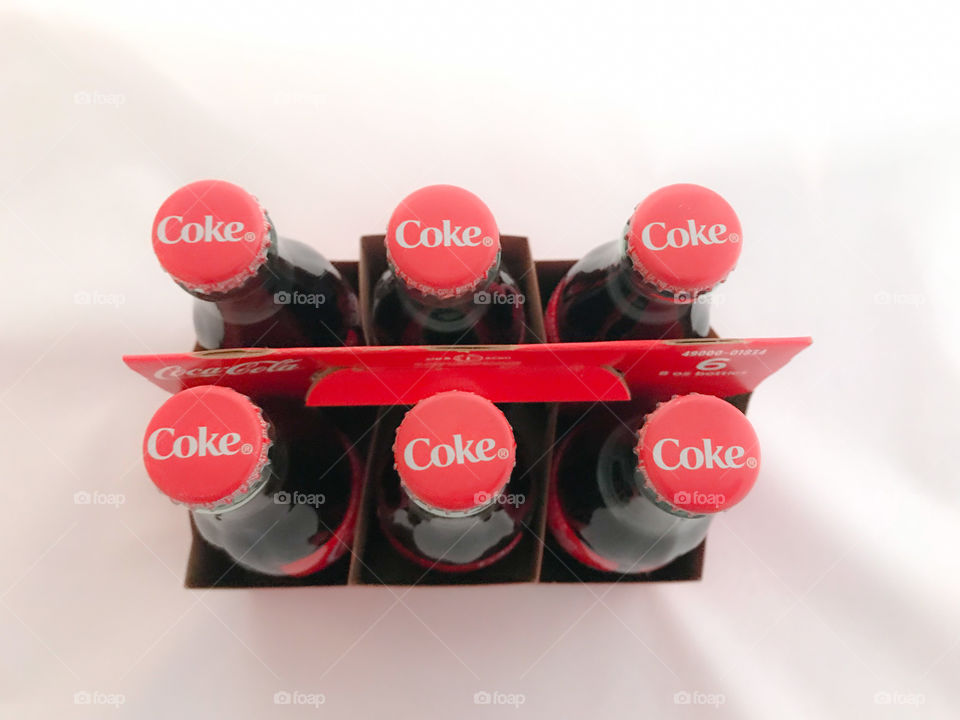 6 pack Coke bottles with focus on caps