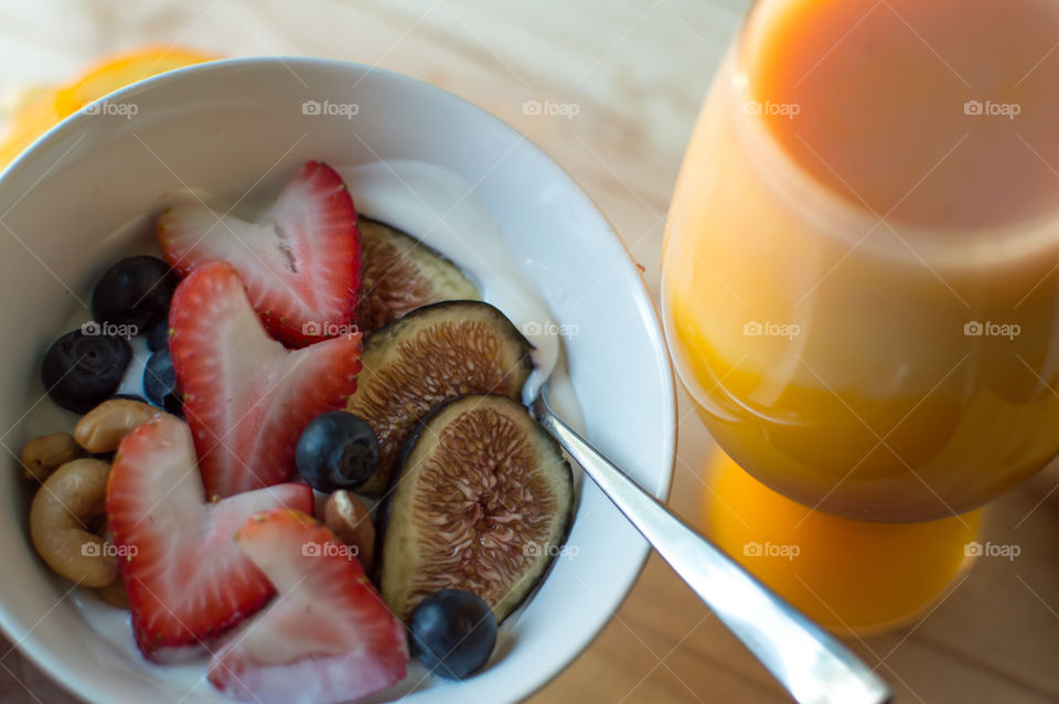 Mango coconut orange blended smoothie and smoothie bowl with cashew and almond butter fresh fig, heart shaped strawberry and blueberries 