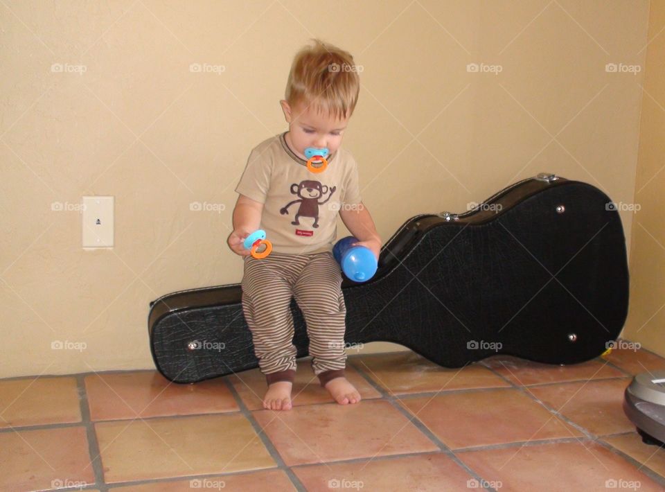 Toddler sitting on guitar case 