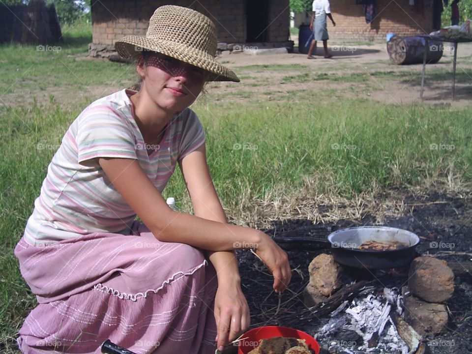 Girl cooking outdoors in African village.