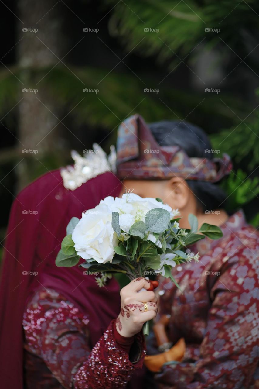 The bride and the groom posing like kissing at a photoshoot outdoor session on wedding day.