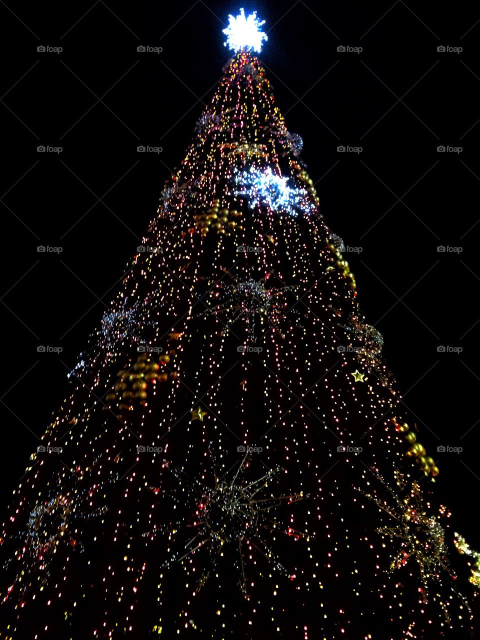 Bright colored illumination on artificial Christmas fir tree in the evening on black sky background in Moscow, Russia