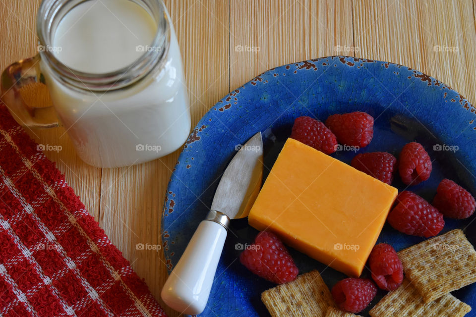 Cold glass of milk with plate of fruit and cheese