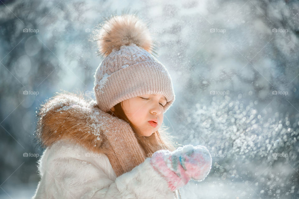 Little girl blowing snow