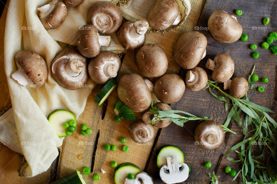 Abundance of mushrooms green peas and sliced mushroom with zucchini healthy vegetable flat lay on rustic wood cooking at home food art photography background 