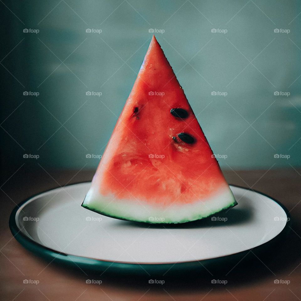 A juicy slice of a watermelon sat on a small plate.