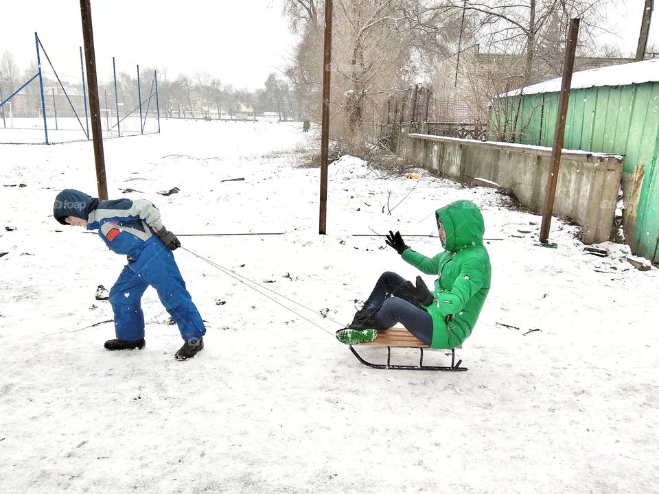 Son rolls mom on a sled
