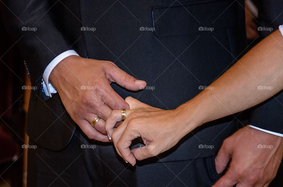 Bride and groom joining hands with their rings during the wedding 