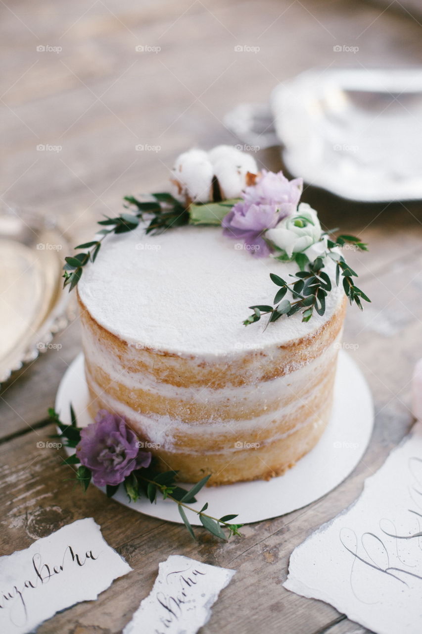 Graphic arts of beautiful wedding calligraphy cards and round cake with floral decorations on wood background