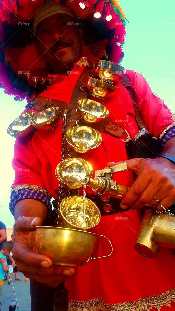 Man in traditional wear pouring water in bowl