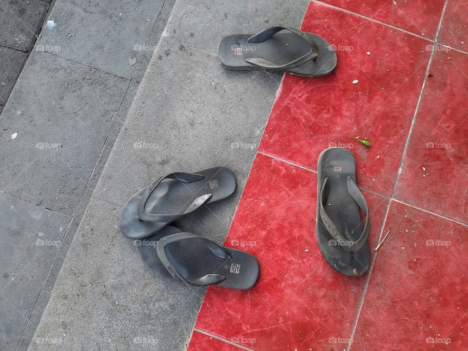 Two pairs of rubber sandals on the red floor.