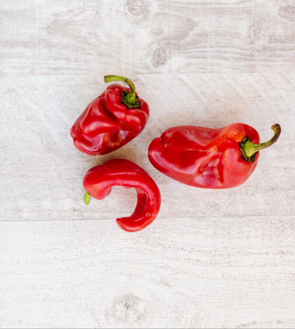 Top view of three ugly fresh and ripe peppers on wooden background. Concept of zero waste.