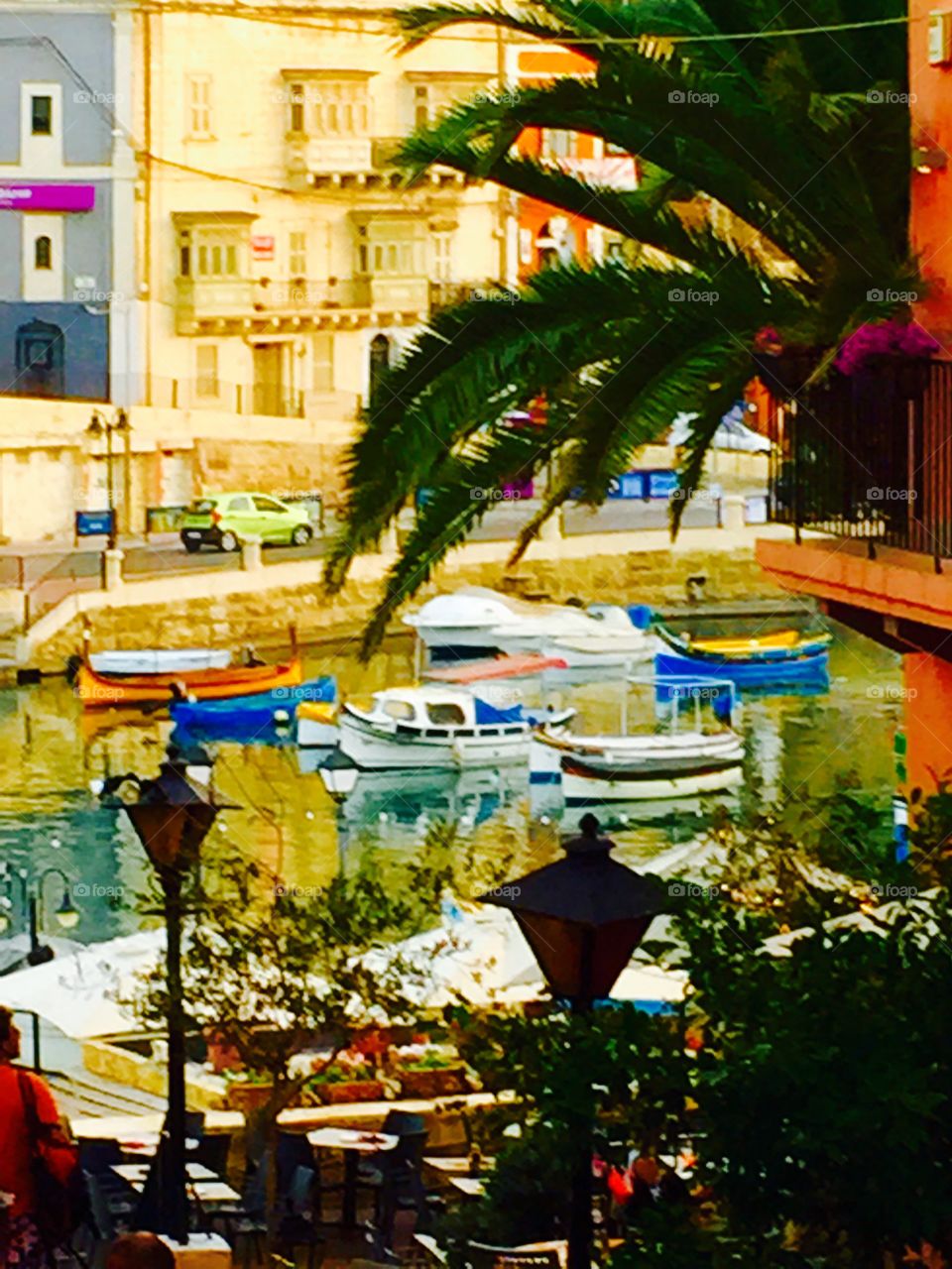 Local Colours. View of the boats in Spinola Bay, Malta, through gap between buildings.