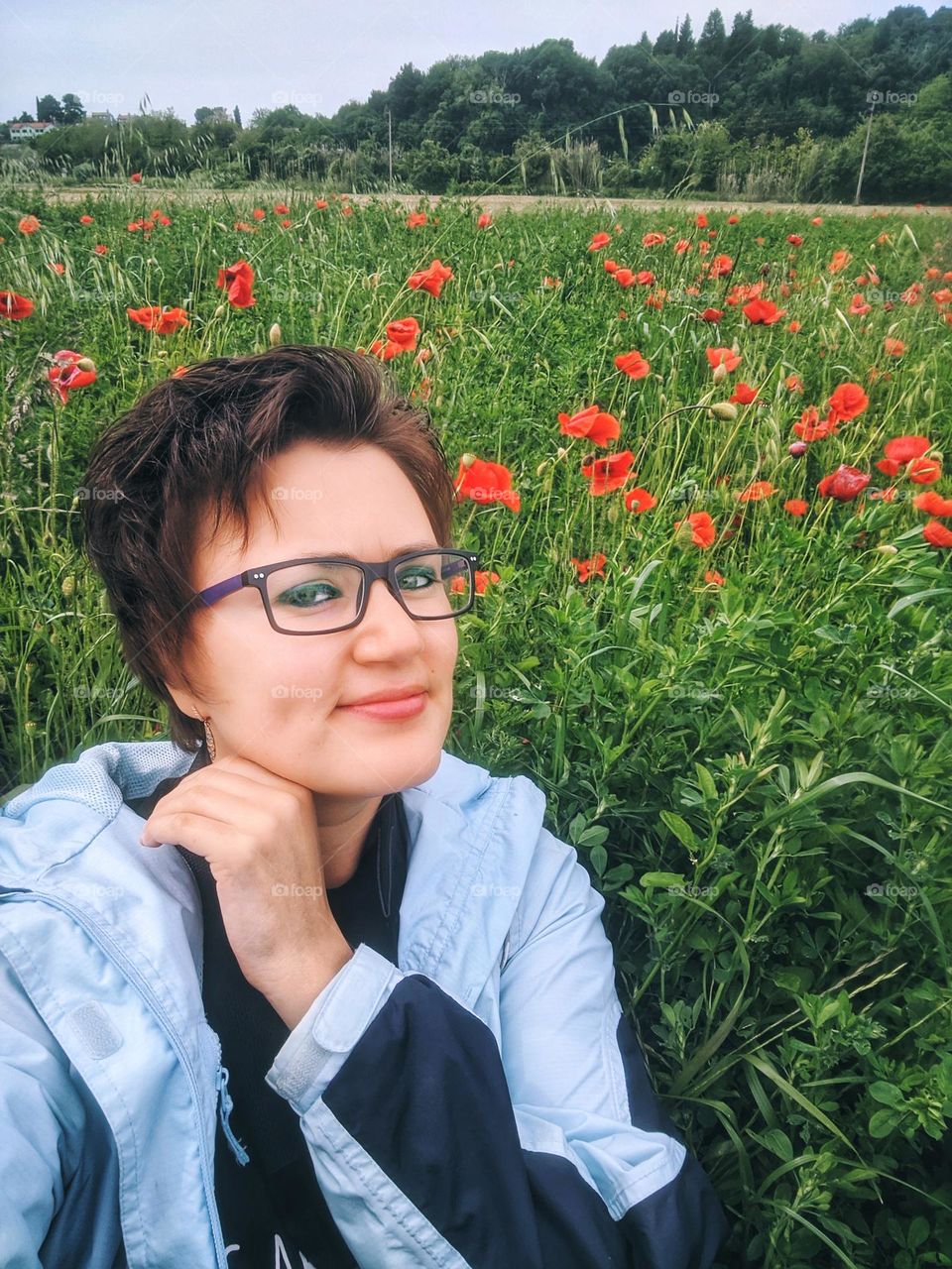 Portrait of beautiful young redhead woman in field with red poppies.  summer meadow in village