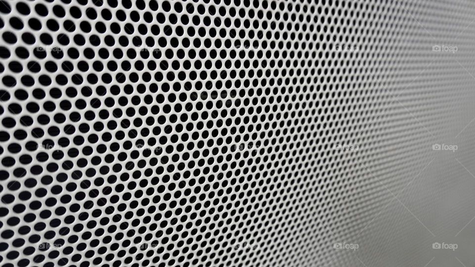 White texture mesh grille design on black background with circular holes