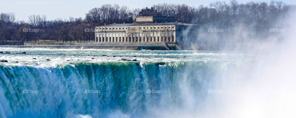 Water rushing over the falls with the power station in the background