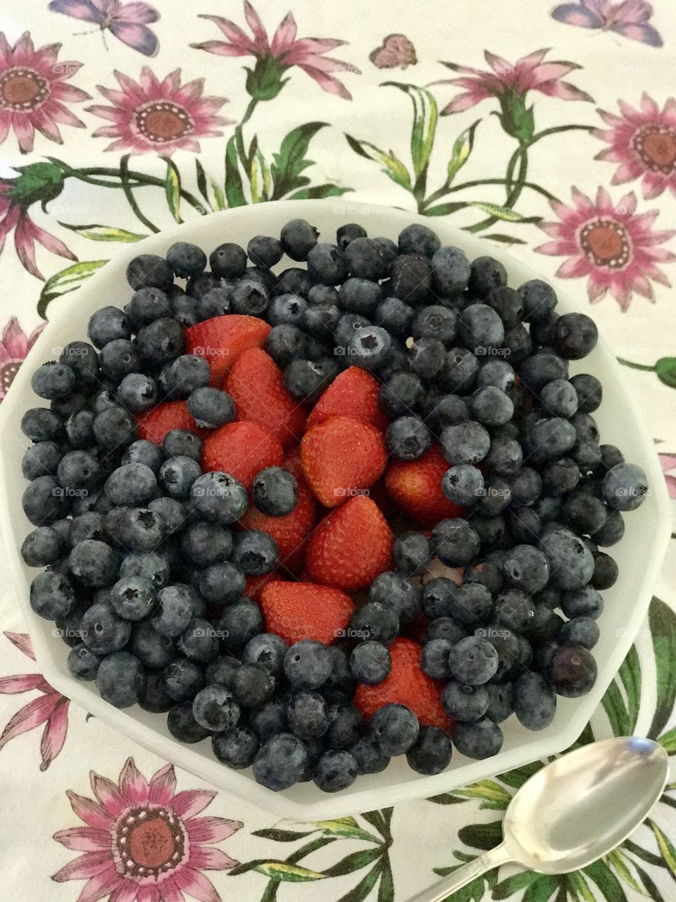 Big fruit bowl of fresh strawberries and blueberries on pretty tablecloth 