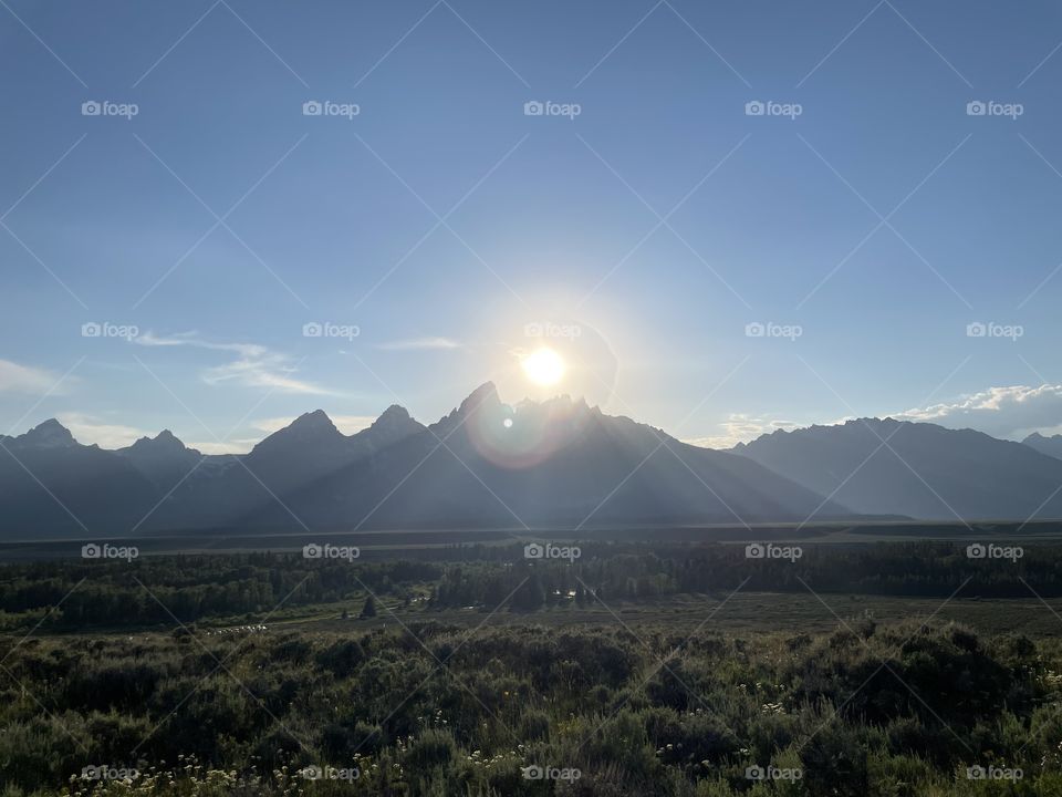 Sunsetting sunset sun over mountain mountains view scenic land prairie landscape fields bushes sky blue clouds sunrise