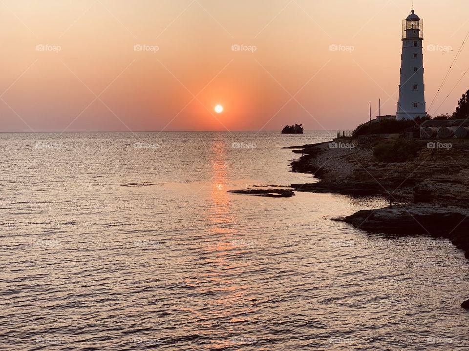 sunset on the sea. lighthouse on the rock