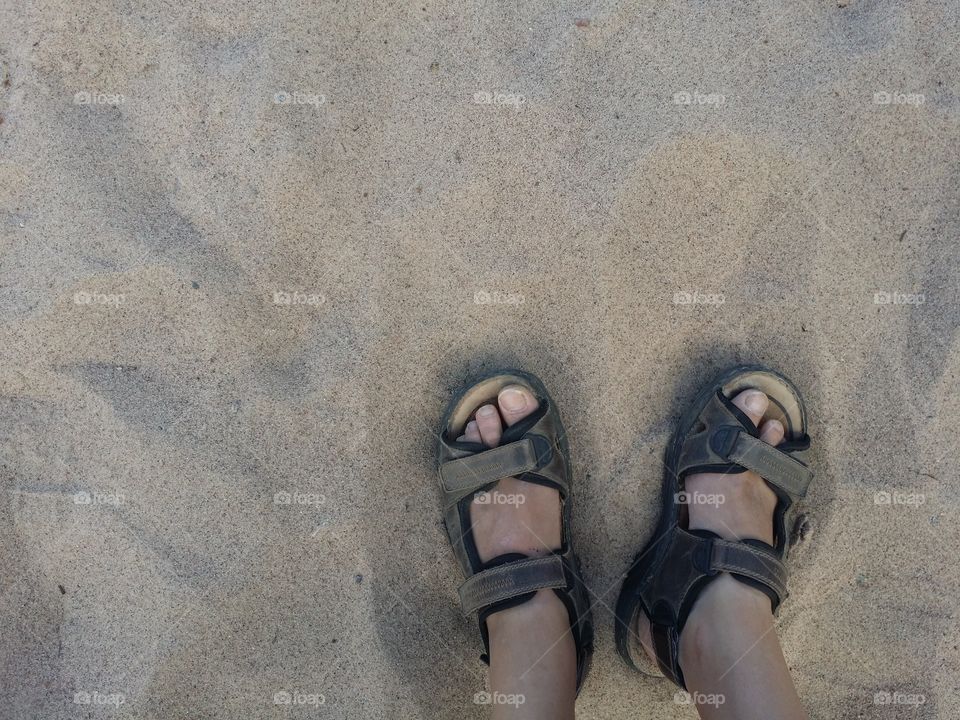 Feet wearing sandals in sand