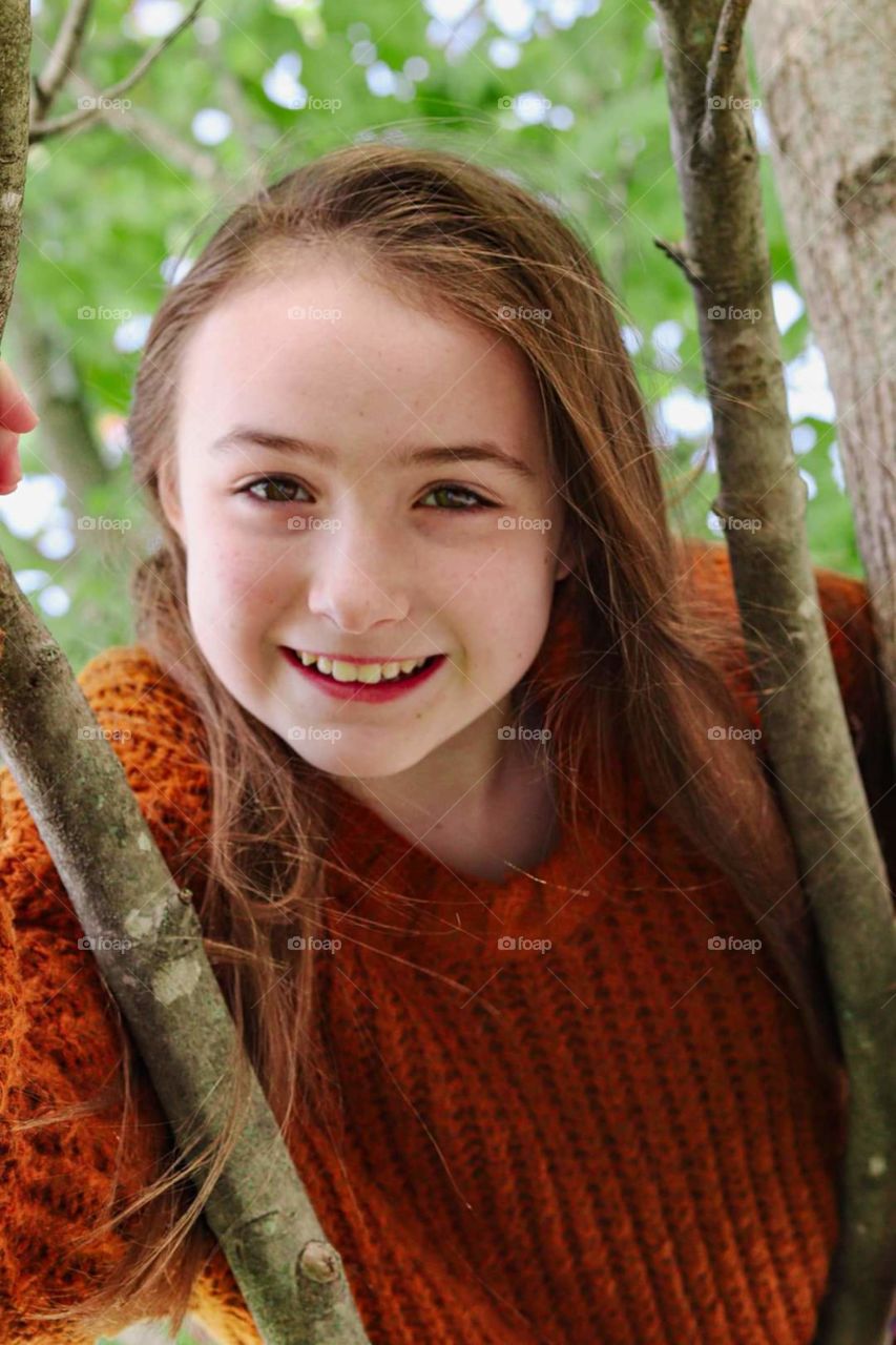 girl in orange sweeter in a tree