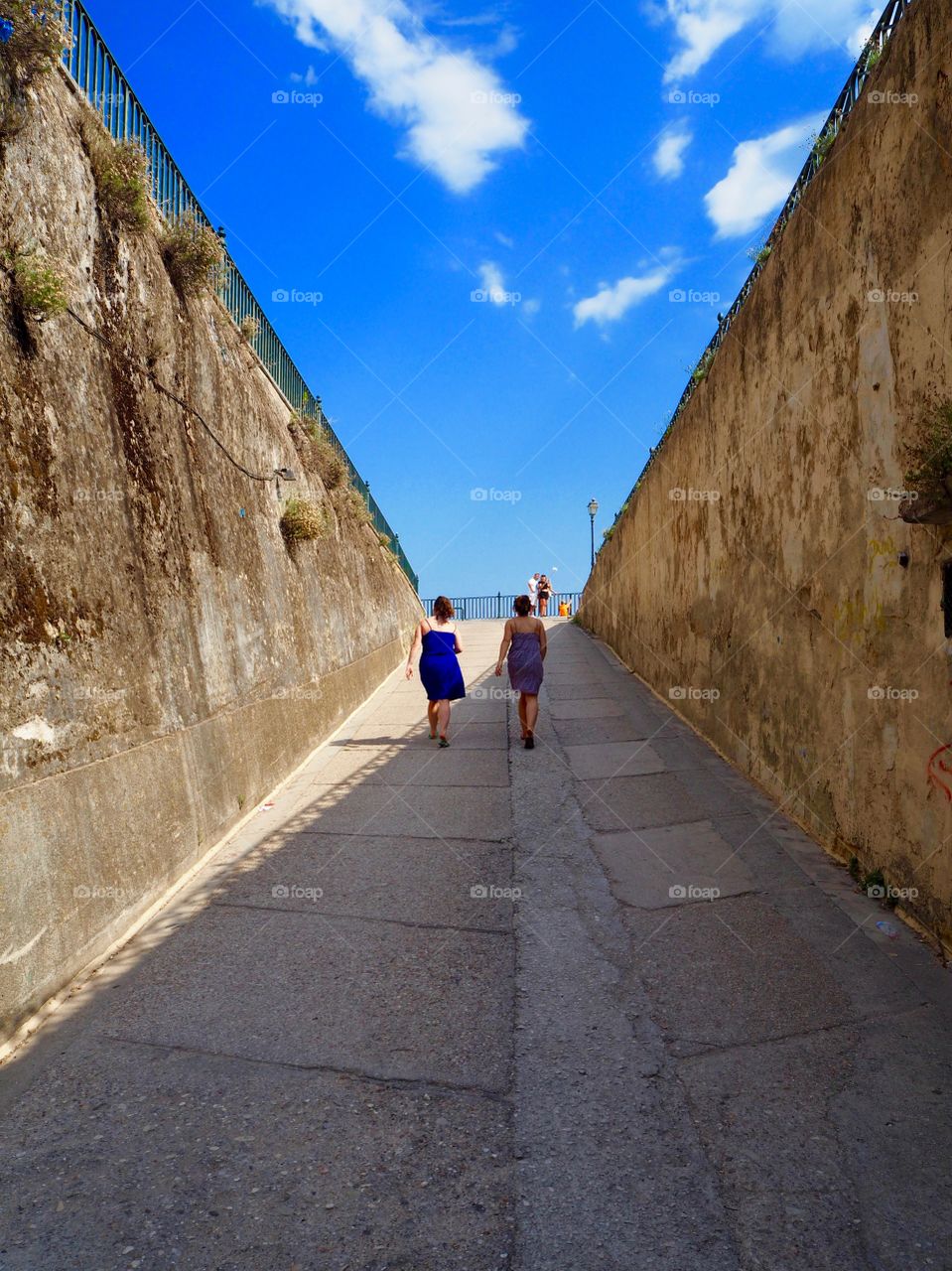 Two girls ascending a walkway in the sun, Corfu Town, Greece