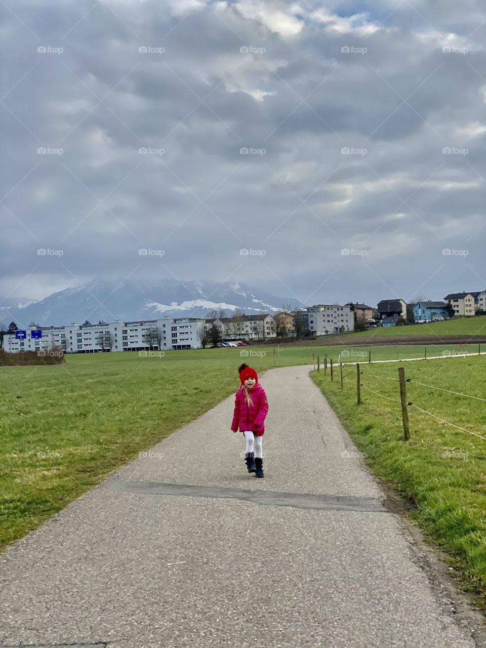a girl in pink walks along the road