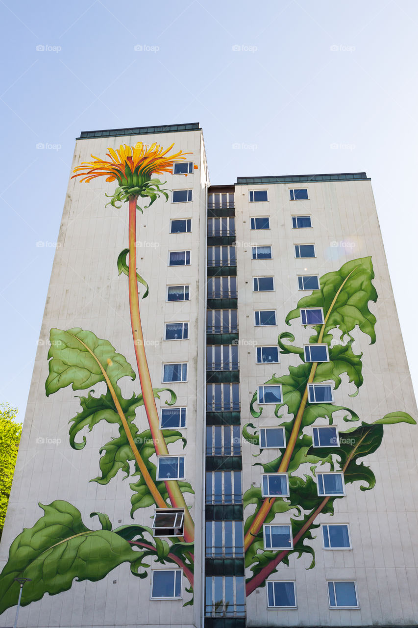 Beautiful painting of dandelion on the facade of a high apartment building