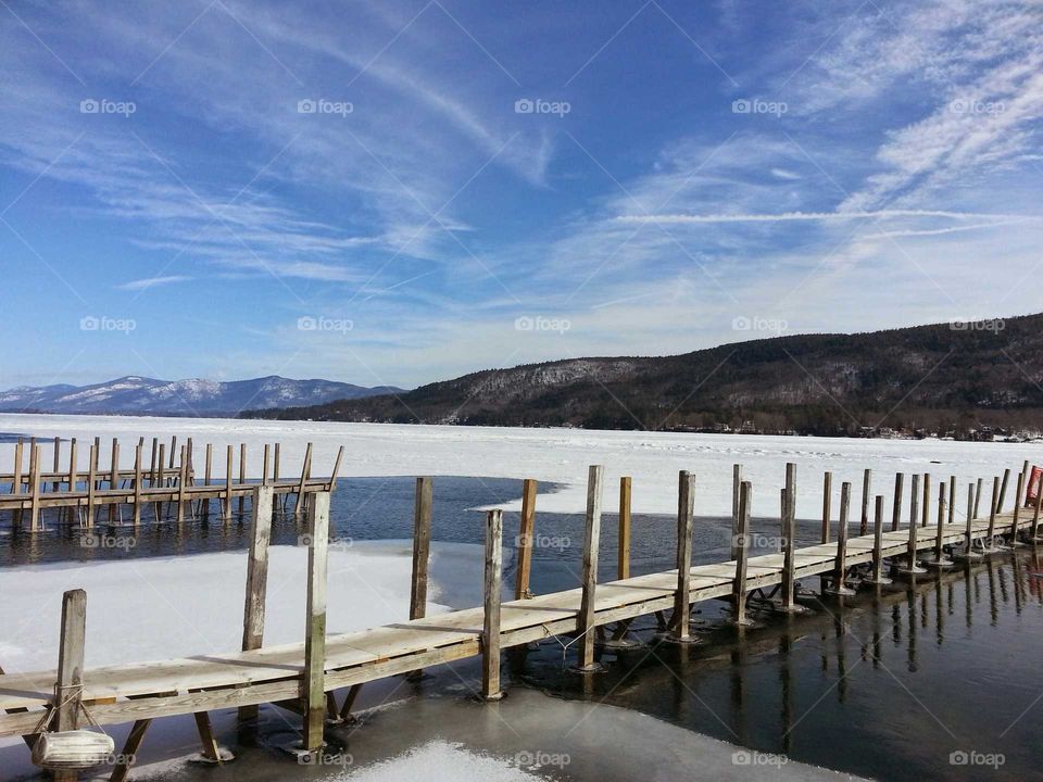 Docks around Lake Georges during winter with mountains and a blue sky