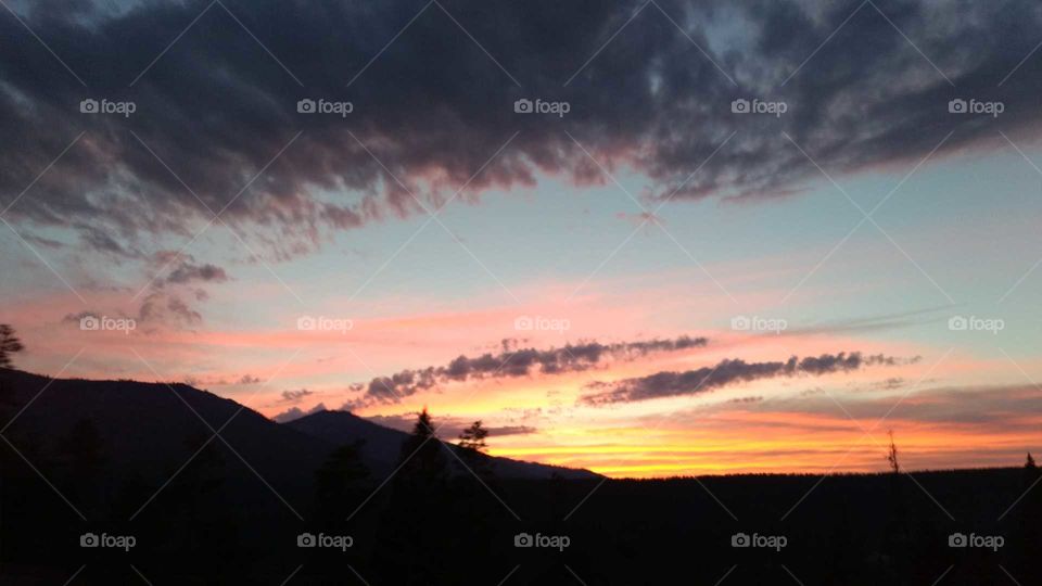 Night sky set ablaze with the rich hues of a fiery sunset of bright pink, orange and yellow and framed with purple clouds.