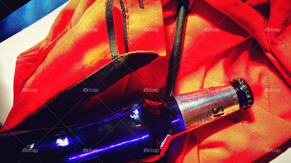 Garrafinha long neck azul sobre uma camisa vermelha.