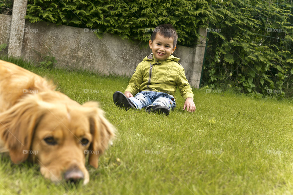 young boy sitting on the grass with his dog on the garden