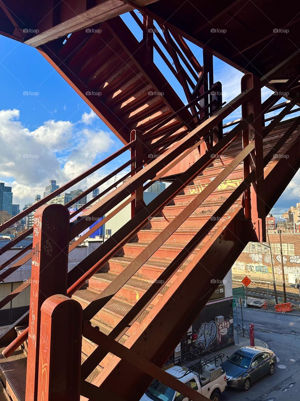 This is the red metal staircase of the “Pulaski Bridge” at “Newtown Creek” in LIC, Queens creating intricate shapes and patterns in the sunlight including the resulting shadows. 2023. Hypnotic Productions