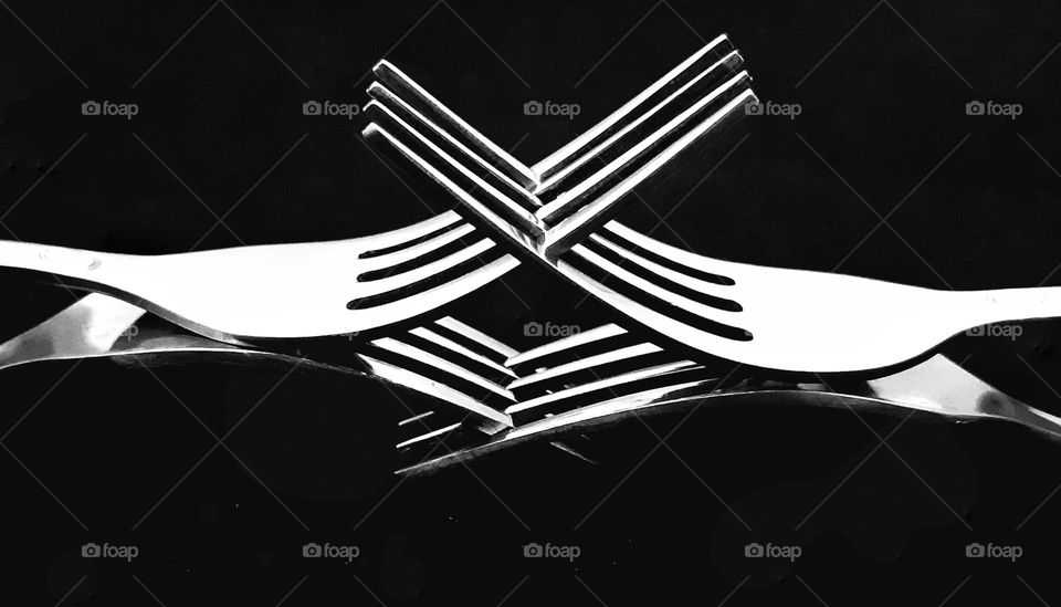 Close up four forks piled and crossed isolated on black background. fork made from stainless steel