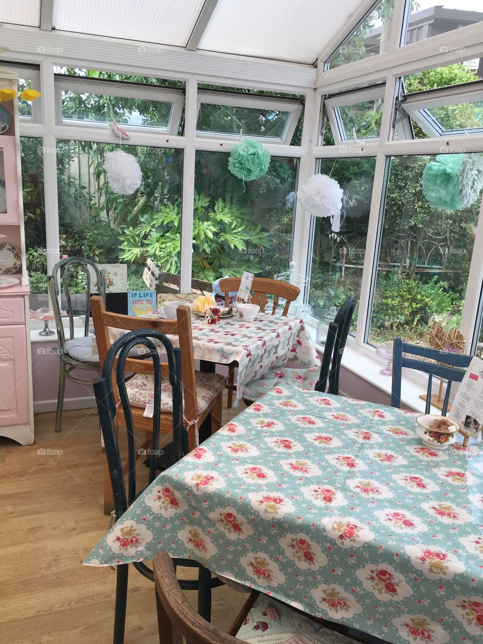 Vintage chic tea room with tables and chairs with pretty tablecloths and decorations hanging in the windows