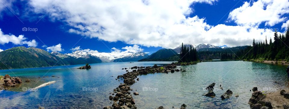 A gorgeous turquoise coloured glacial lake surrounded by tall peaks, alpine meadows and evergreen forests.