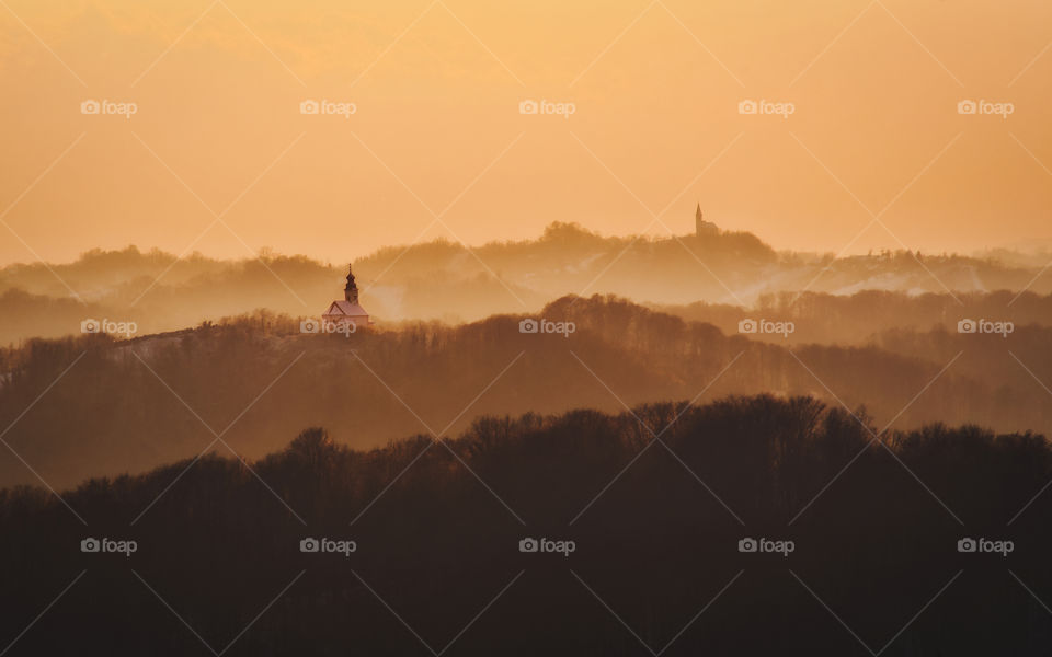 Beautiful orange sunset scenery of churches on the hills in Croatia, county hrvatsko zagorje