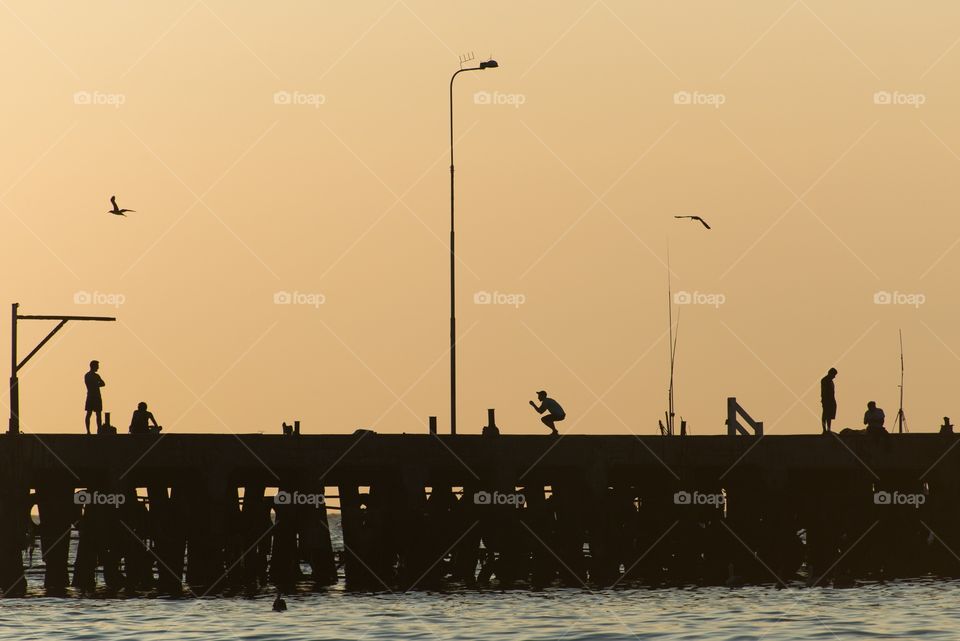 Silhouettes of people on a pier 