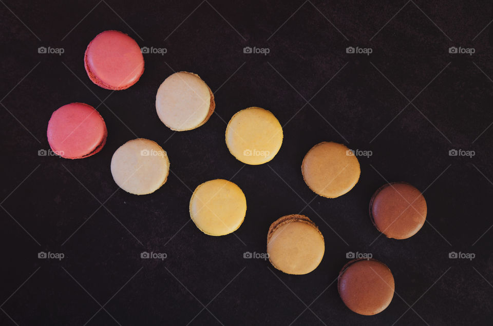 Background of the colorful delicious macaroons at dark table close up. Womans day. Greetings card. Flat lay.