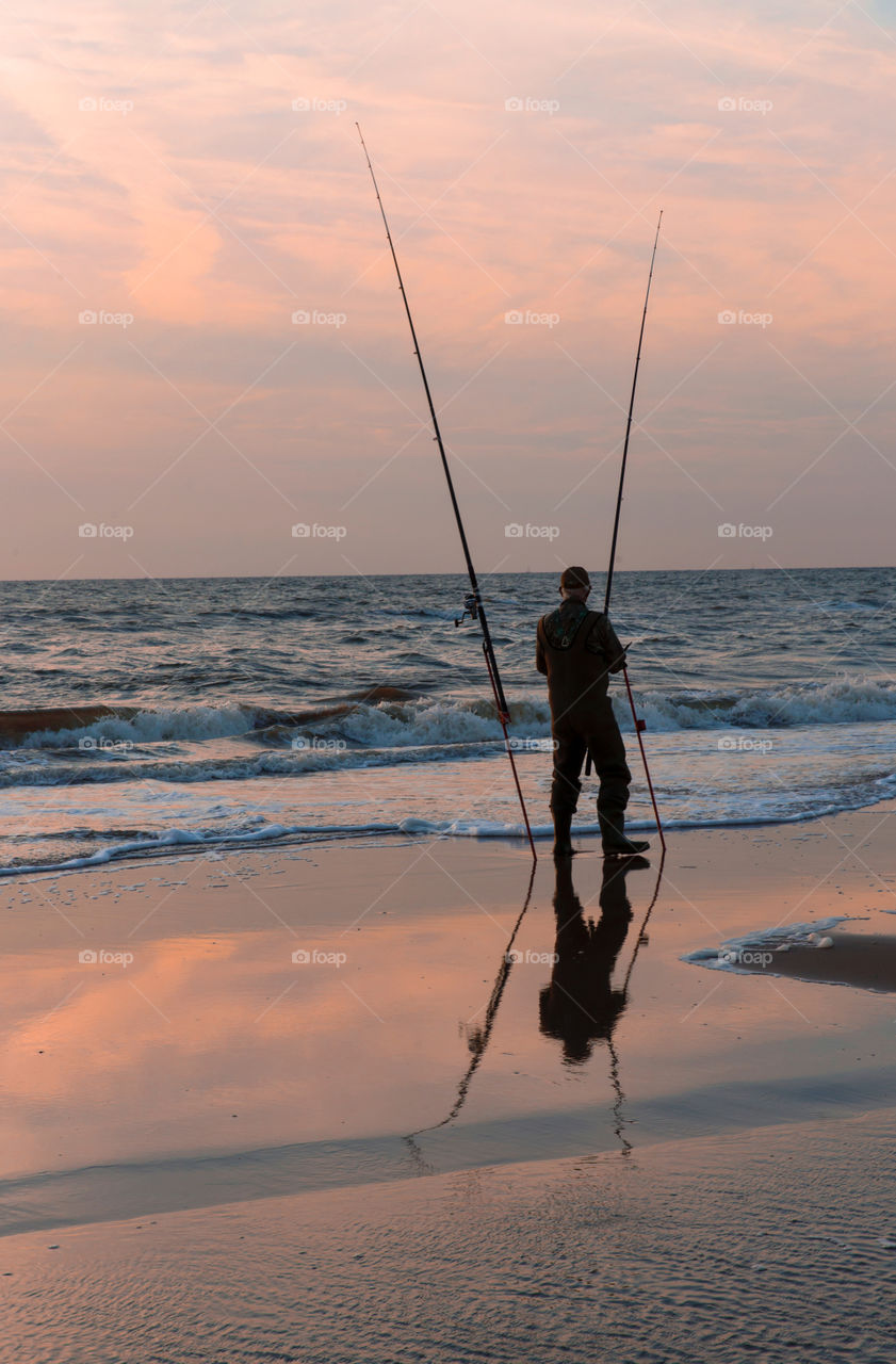 Fisherman and his reflection at sunset