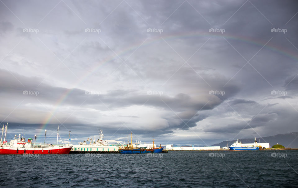 Reykjavik harbour during a storm with rainbow and cargo vessel
