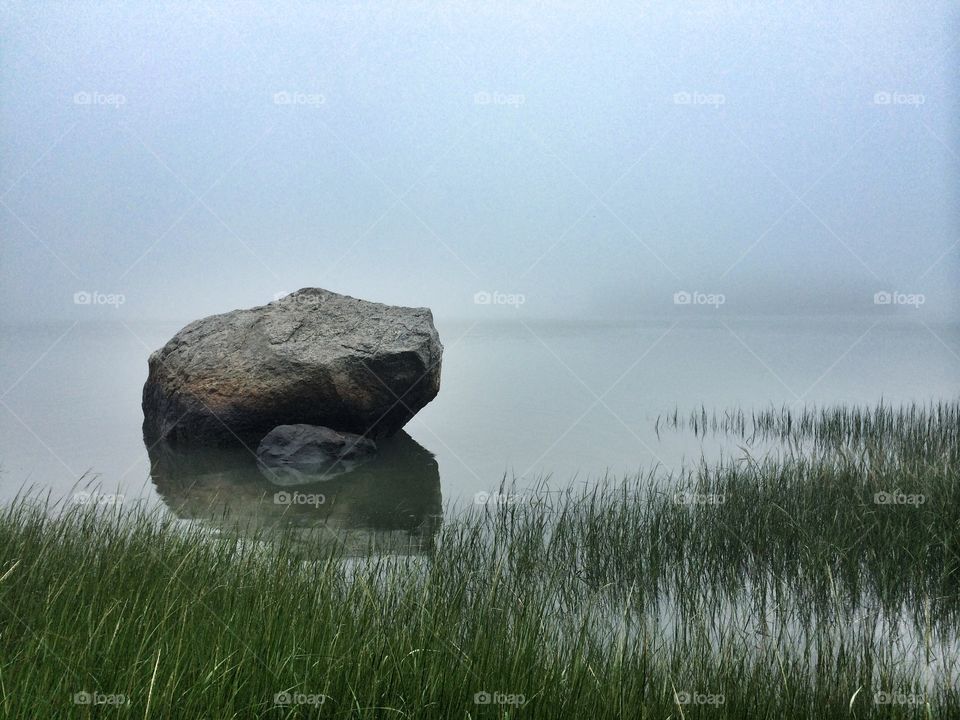 Rocks on lake during foggy weather