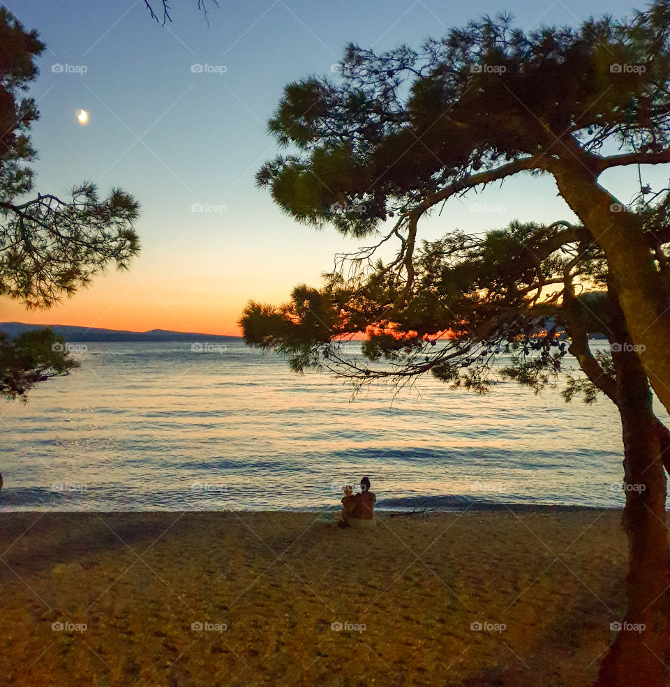 Mom with a small daughter looking into the distance on the seashore in the evening.  Summer family vacation at sea