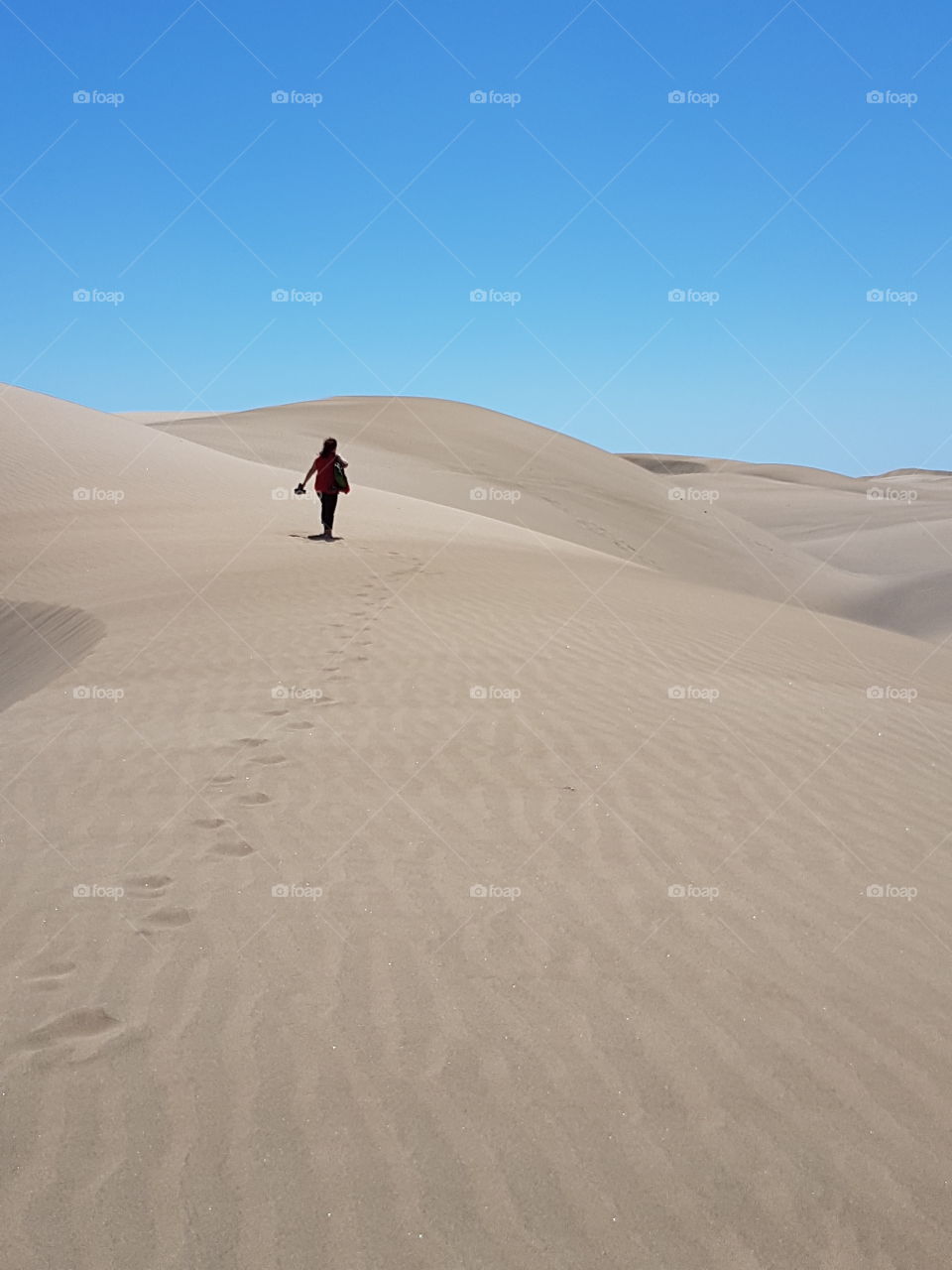 woman walking on sand, footprints on dry sandy desert Beach in Canary Islands