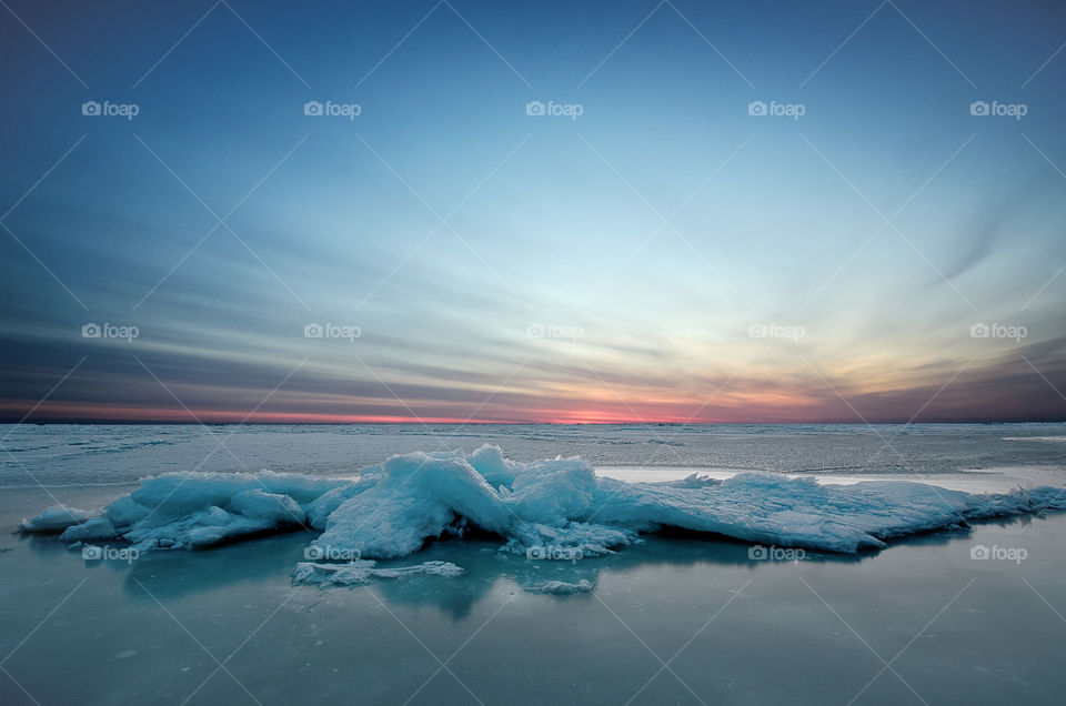 frozen winter sunrise sescape with ice and colorful sky