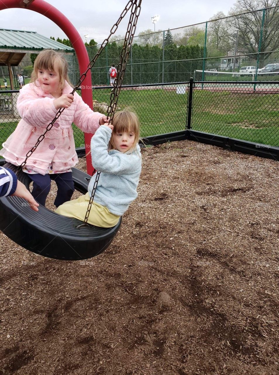 Two biological sisters with Down syndrome swinging 