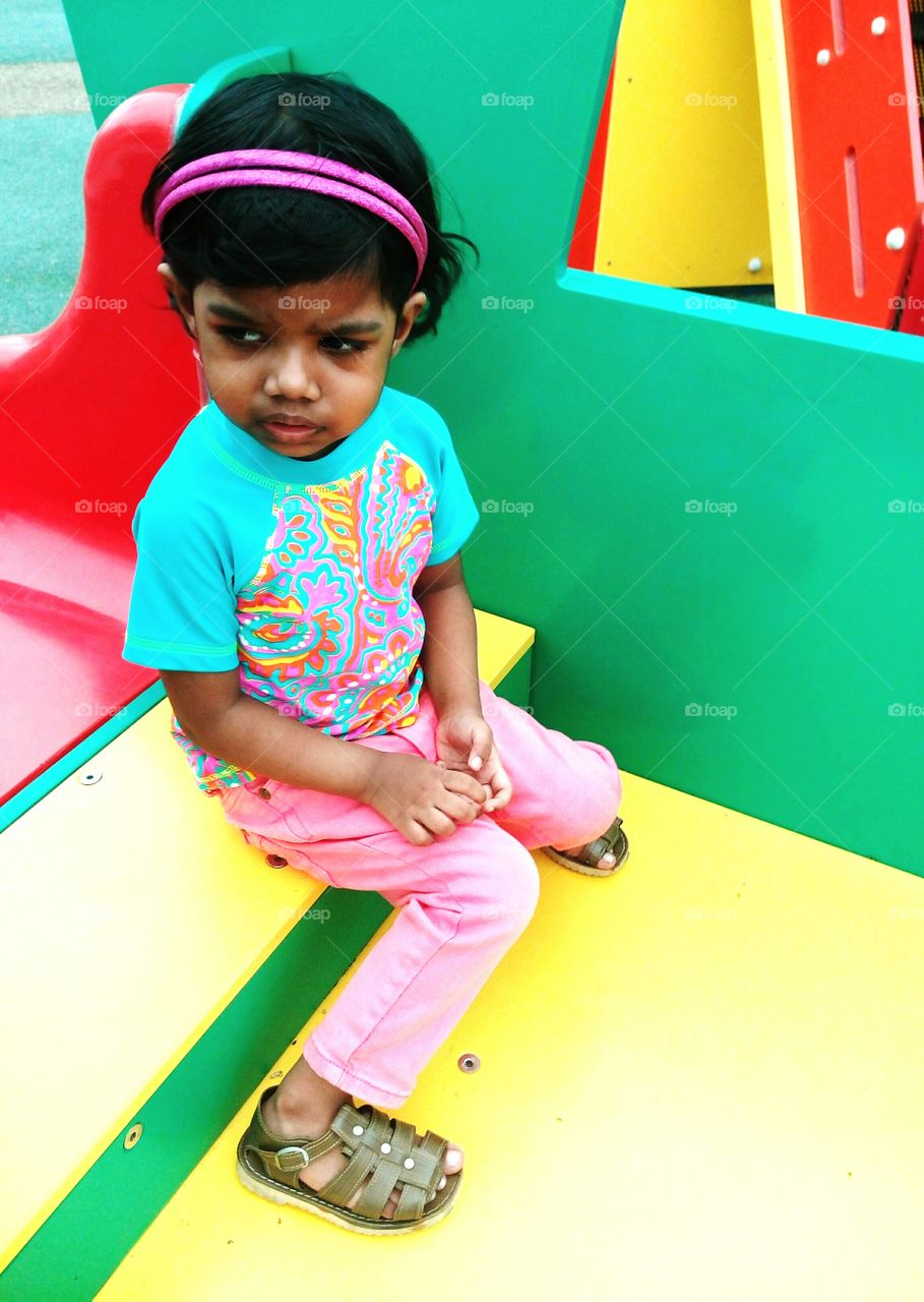 Little girl sitting alone, looking sad, scared and about to cry