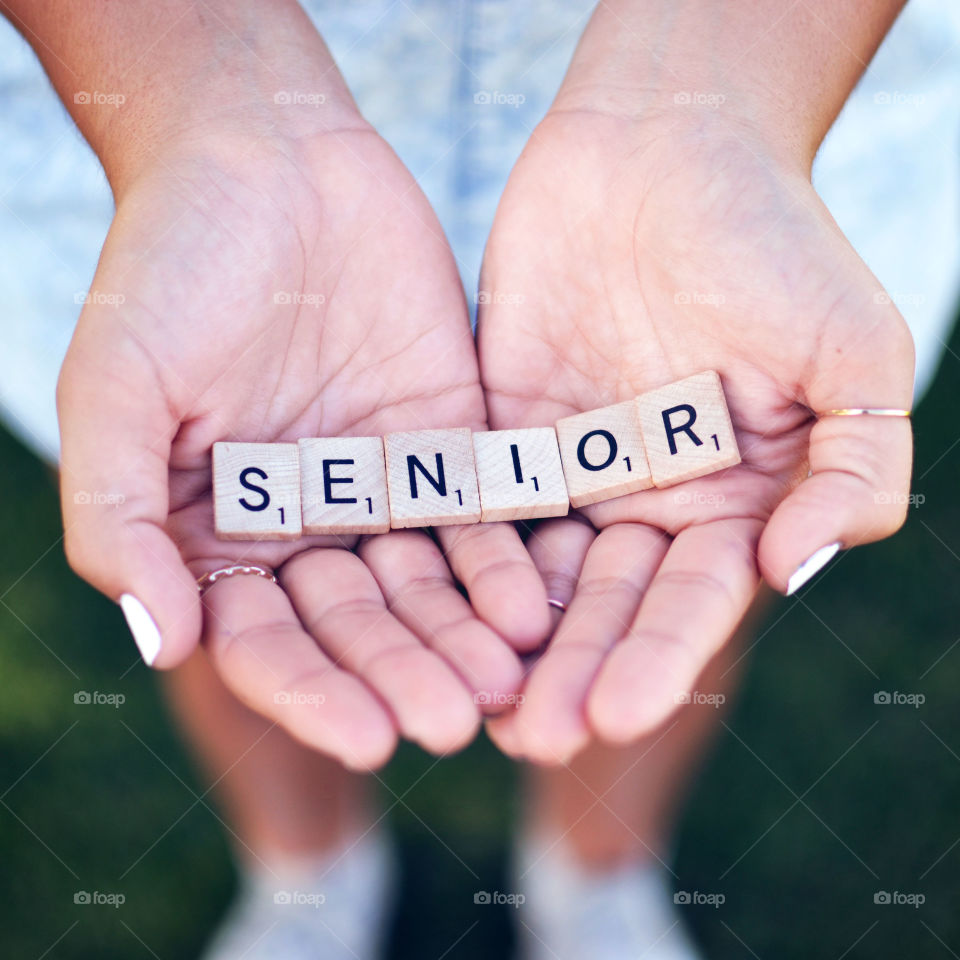Senior. Hands holding scrabble tiles that spell out senior 