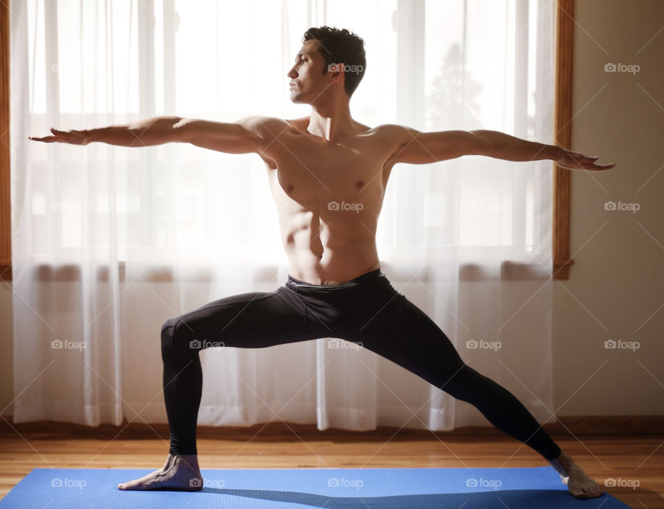 Young shirtless man doing arms exercise on mat